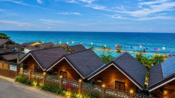 Un hotel sulla costa con diverse cabine in legno, una piscina e vista sull'oceano.