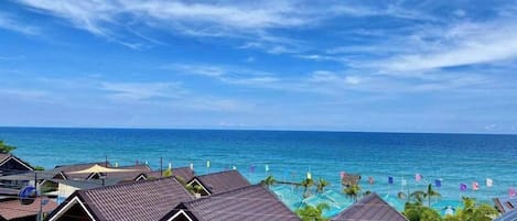 A coastal hotel with multiple bungalow-style rooms, a pool area, and a view of the ocean.