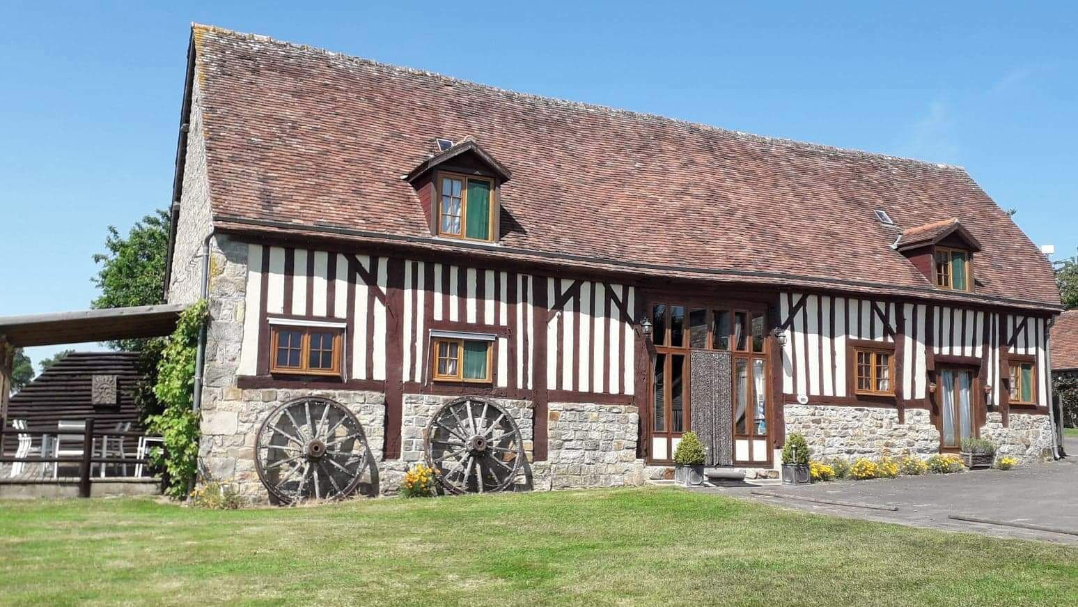 A traditional half-timbered building with stone walls, wooden beams, and two large wooden wheels.