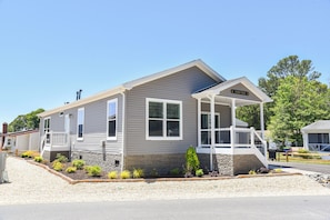 Ein Bungalow mit Veranda, einem kleinen Garten und blauem Himmel.