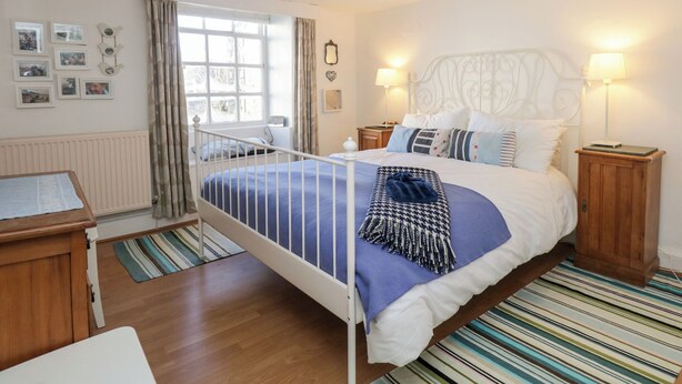 Een slaapkamer met een bed, nachtkastjes, een raam met gordijnen, een radiator en wanddecoraties.