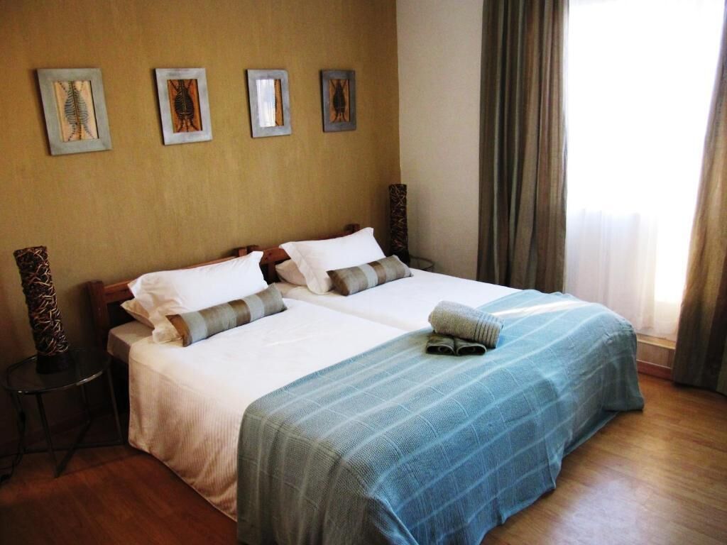Une chambre d’hôtel avec un grand lit, deux tables de chevet et une fenêtre avec des rideaux.