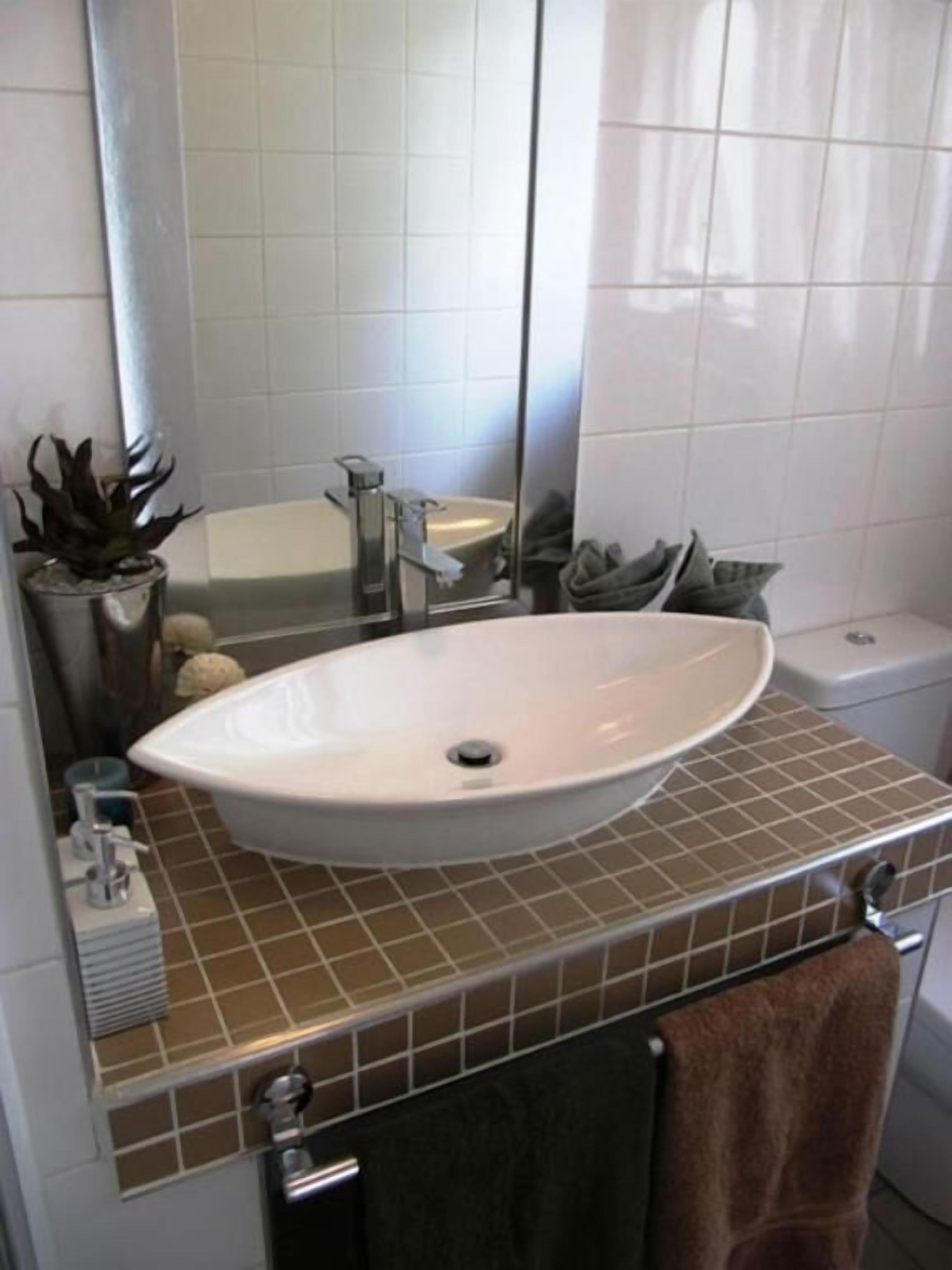 A bathroom with a white sink, a mirror, a towel rack, and a potted plant.