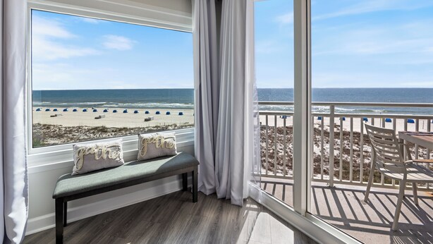 Un balcón con vista a la playa, una banca y una mesa.