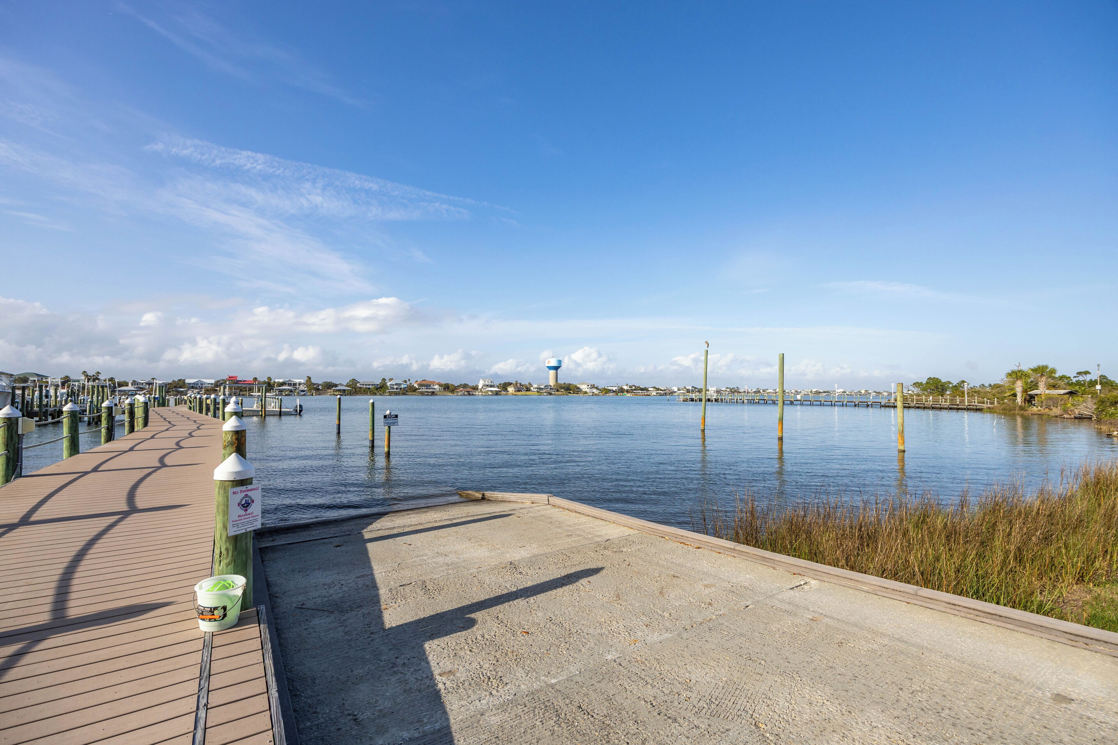 A waterfront walkway with a concrete path, wooden planks, and bollards.