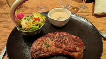 Une assiette avec un steak grillé, une salade en accompagnement et un petit bol de sauce.