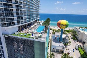A hotel with a pool area, a beach sign, and a view of the ocean. - Beachfront Luxe Condo Sunrise Oceanfront Balcony (Hollywood)