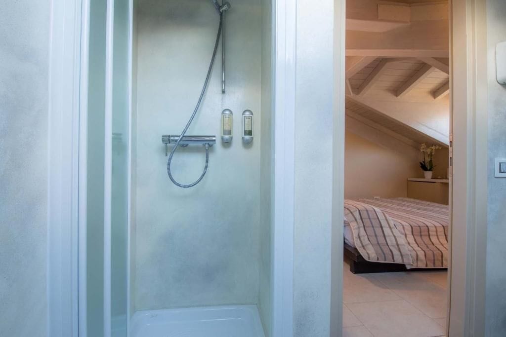 Un baño pequeño con ducha, inodoro y una mesita de noche con una planta.