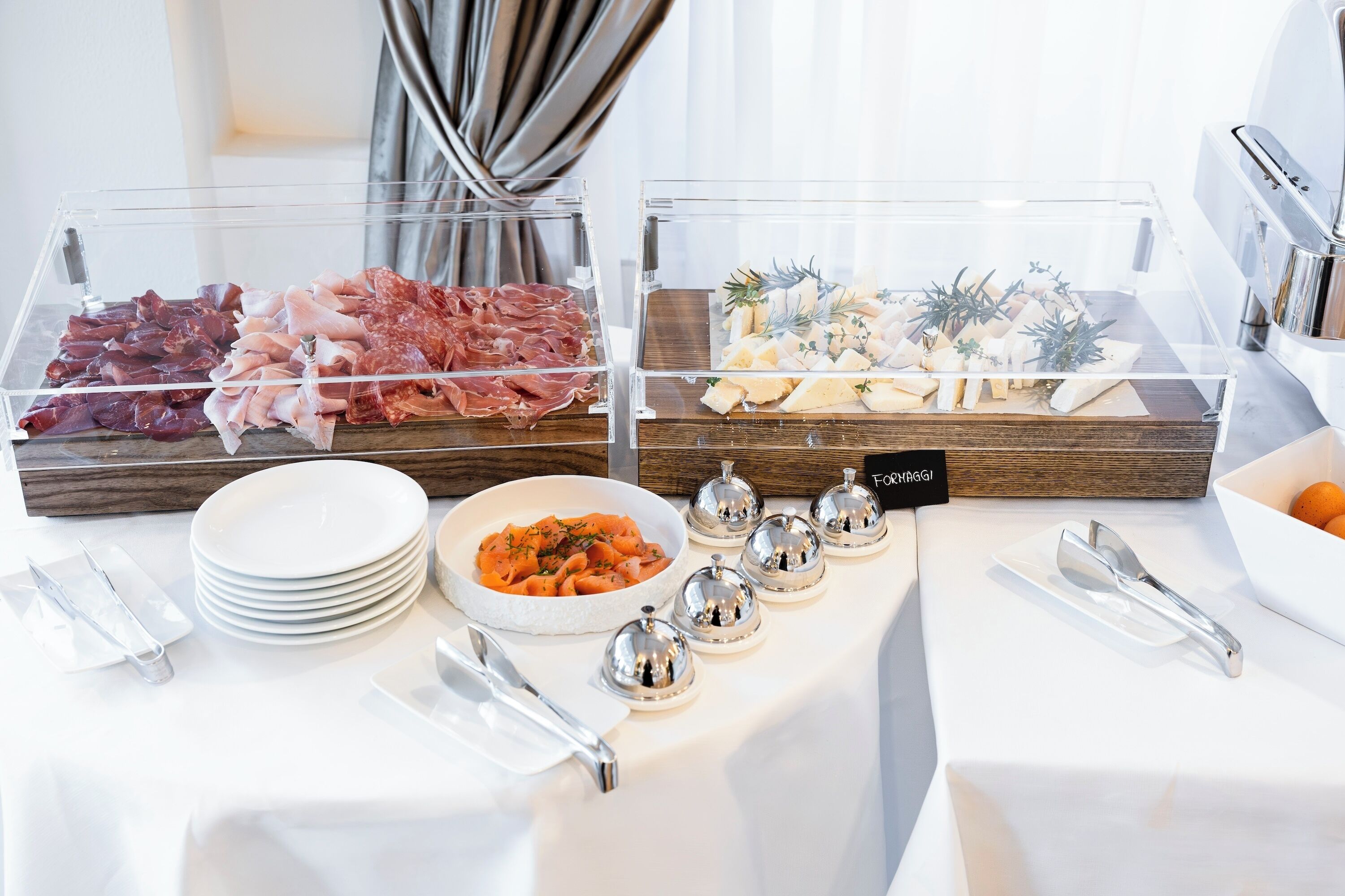 A buffet with various meats and cheeses, neatly arranged in glass display cases.