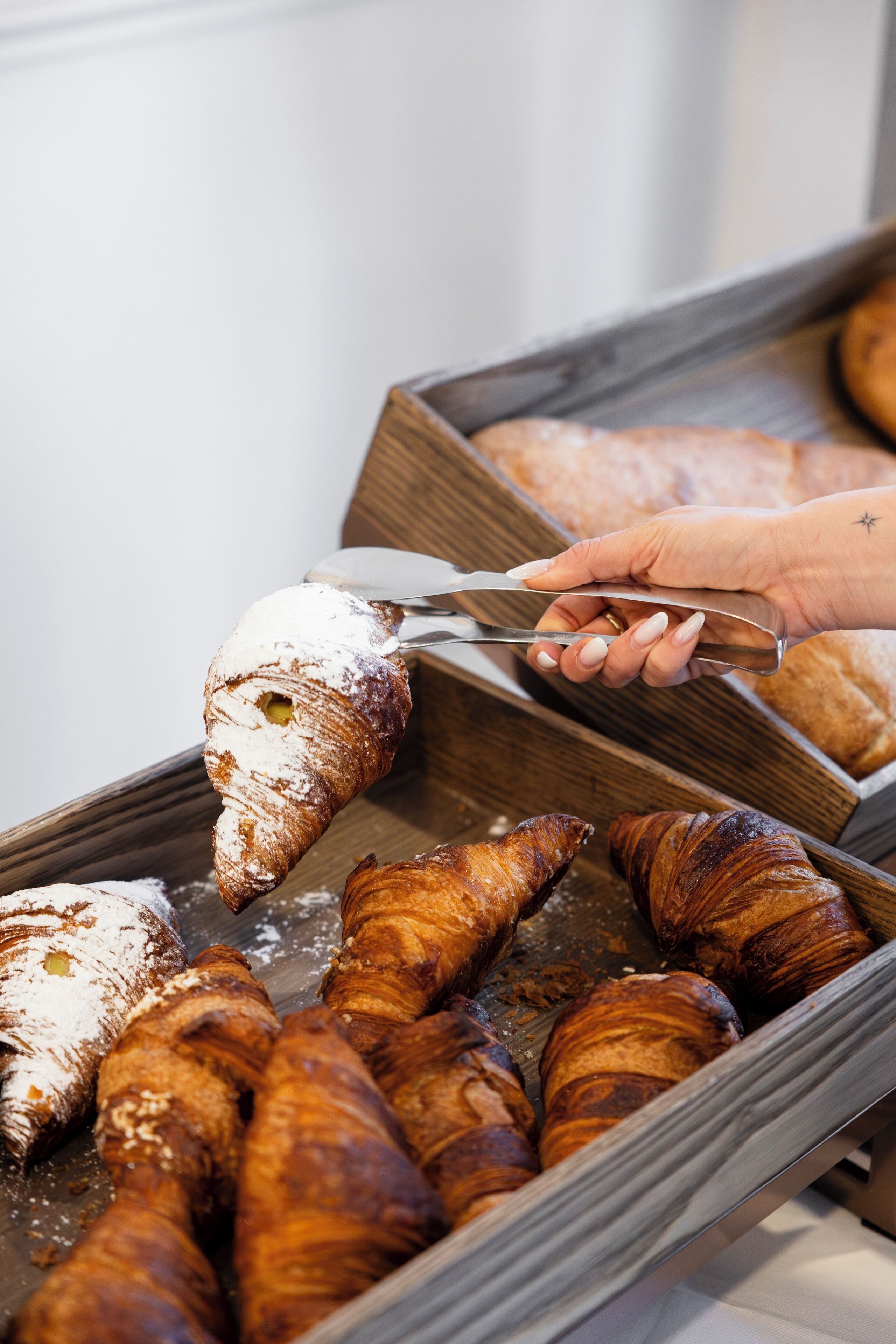 A tray of pastries, including croissants and a pastry with powdered sugar.