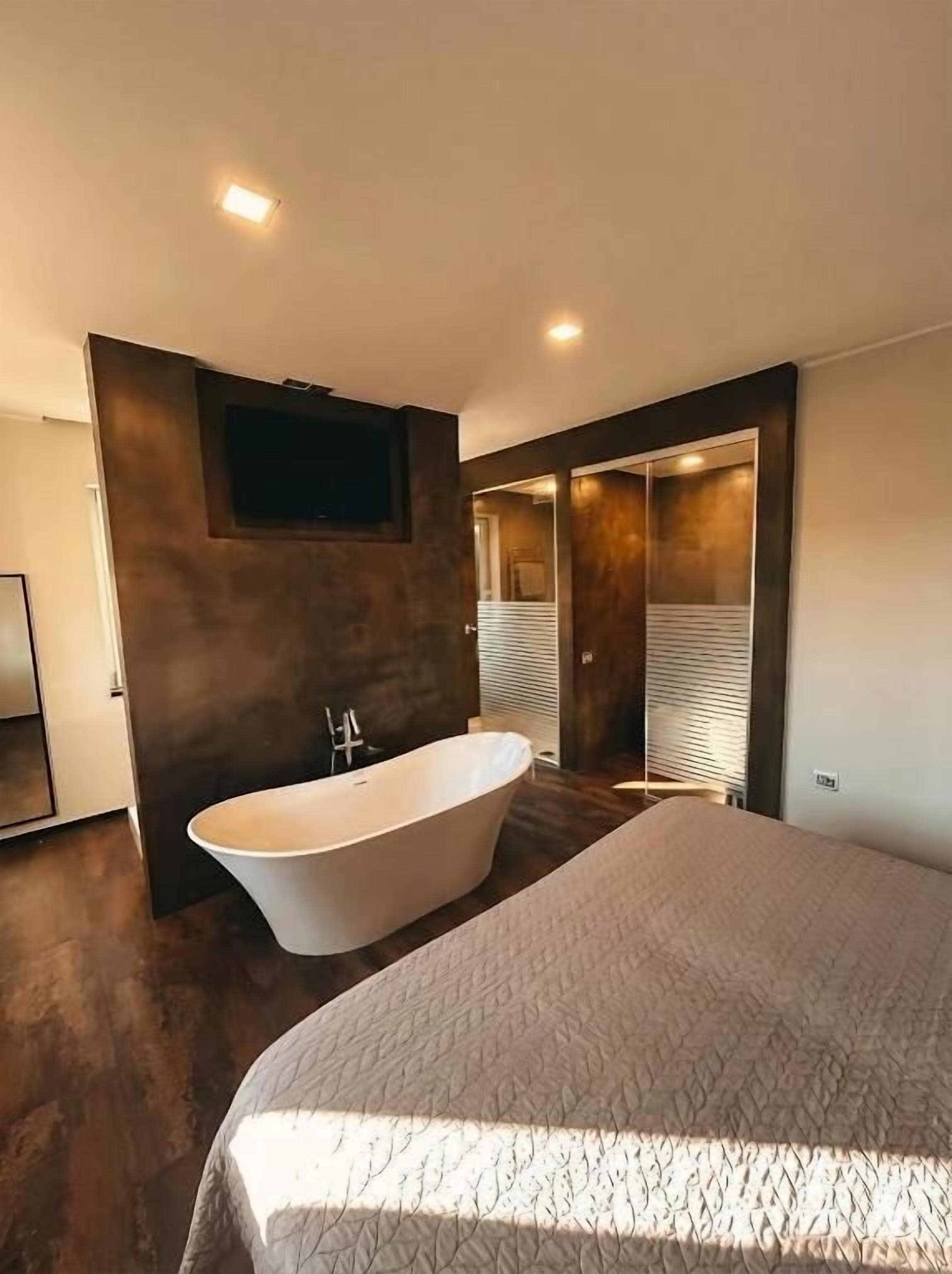 Un dormitorio moderno con una cama grande, una bañera separada y un vestidor.