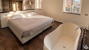 Quarto moderno com cama grande, armário embutido e banheira independente.
