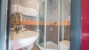 Un baño moderno con ducha envuelta en vidrio, un lavamanos blanco y un inodoro.