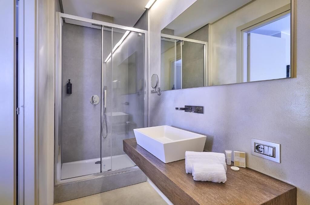 A modern bathroom with a glass-enclosed shower, a large white sink, and a wooden countertop.