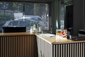 A reception desk with a window view, a chair, and a card holder with a QR code.