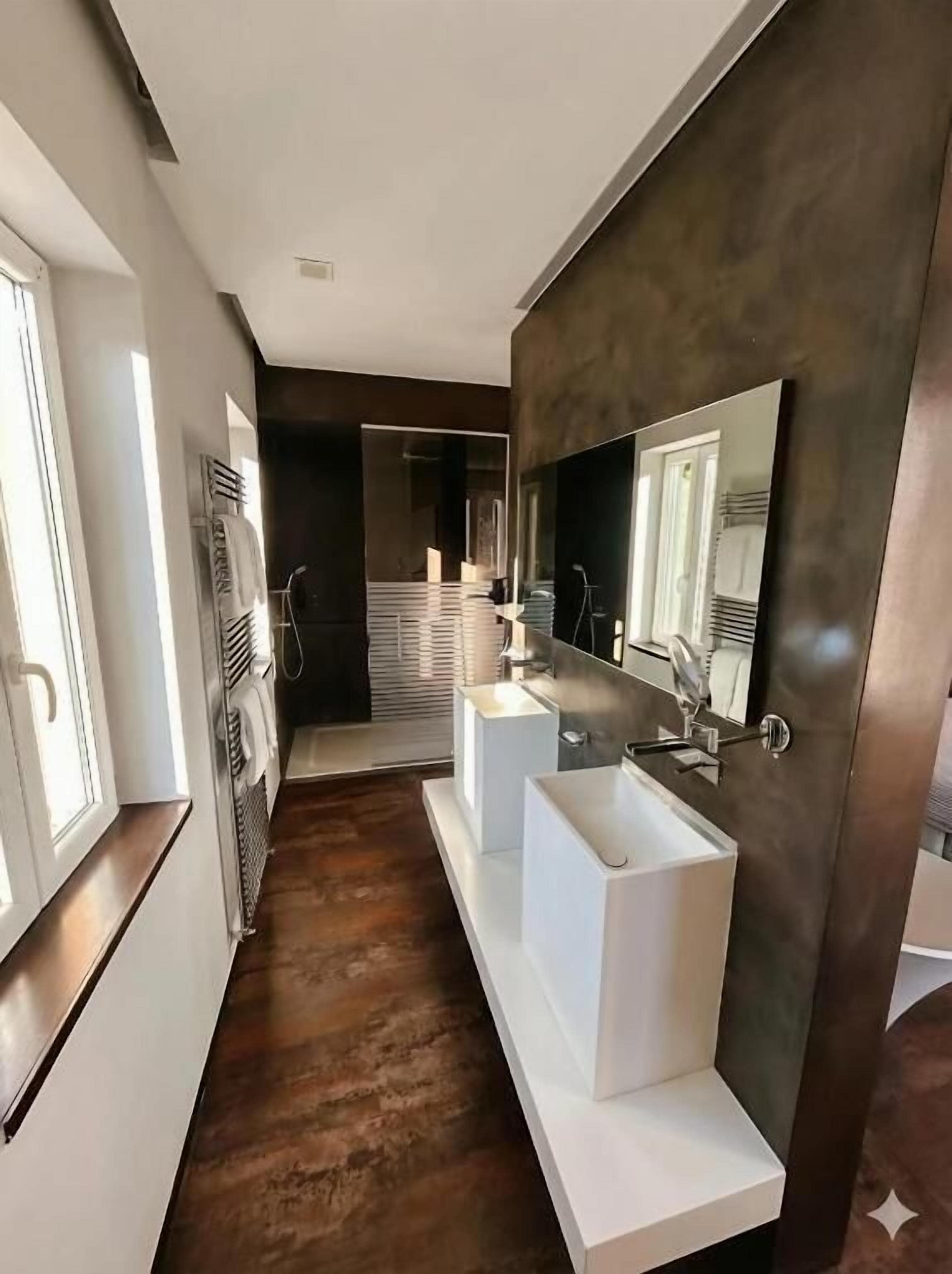 Un baño moderno con un espejo grande, dos lavamanos y una ducha a ras de suelo.