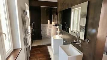 Un baño moderno con un espejo grande, dos lavamanos y una ducha a ras de suelo.