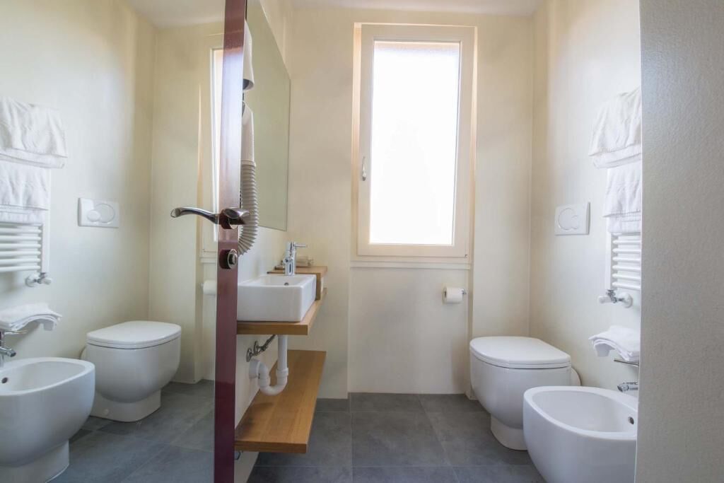 Un baño pequeño con dos inodoros, un lavamanos y un bidé.