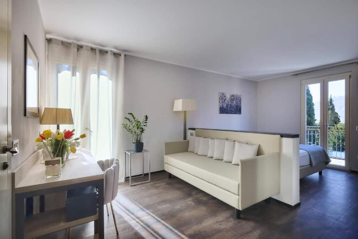A modern living room with a sofa, a small table with a lamp, and a plant.