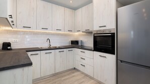 Une cuisine moderne avec des meubles blancs, un réfrigérateur en acier inoxydable, un four à micro-ondes et un four traditionnel.