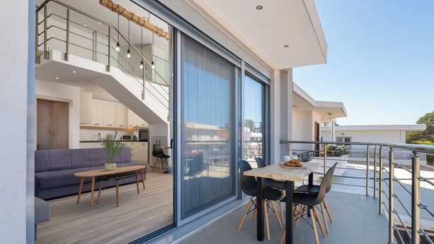 Un intérieur moderne comprenant un coin repas, une cuisine et un balcon doté d’une rambarde.