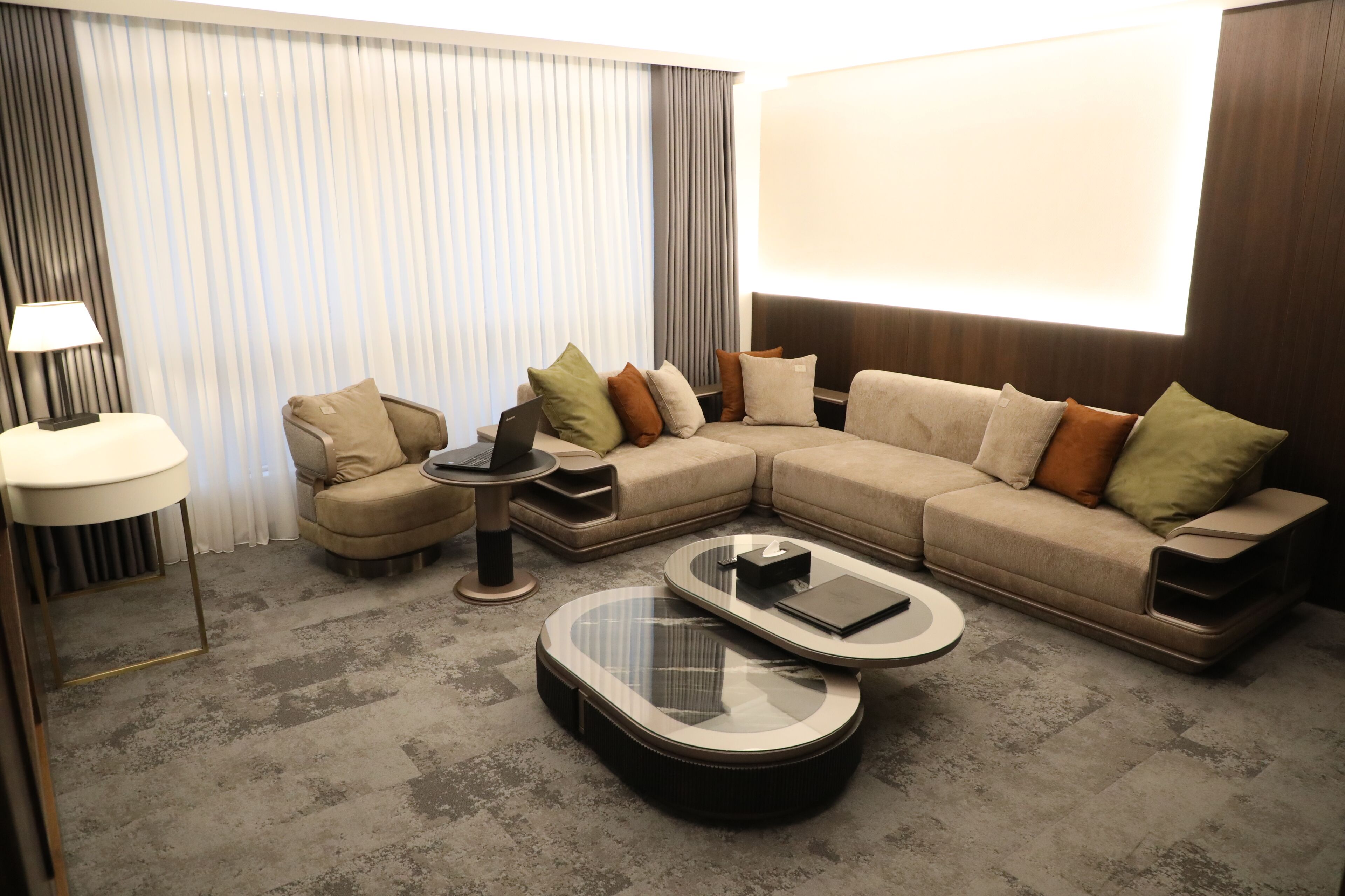 A modern living room with a sectional sofa, two coffee tables, a side table, and a lamp.