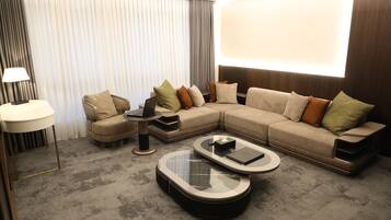 A modern living room with a sectional sofa, two coffee tables, a side table, and a lamp.