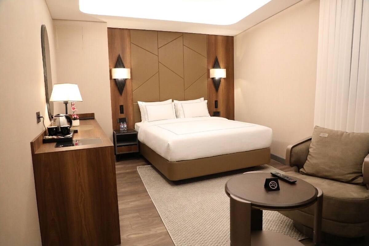 Una camera d'albergo con un letto, una scrivania, una sedia e un tavolino.