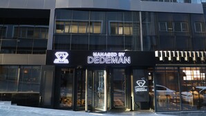 Un bâtiment moderne doté d’une façade en verre, une enseigne indiquant « Exploité par DEDEMAN » et un logo en forme de losange.