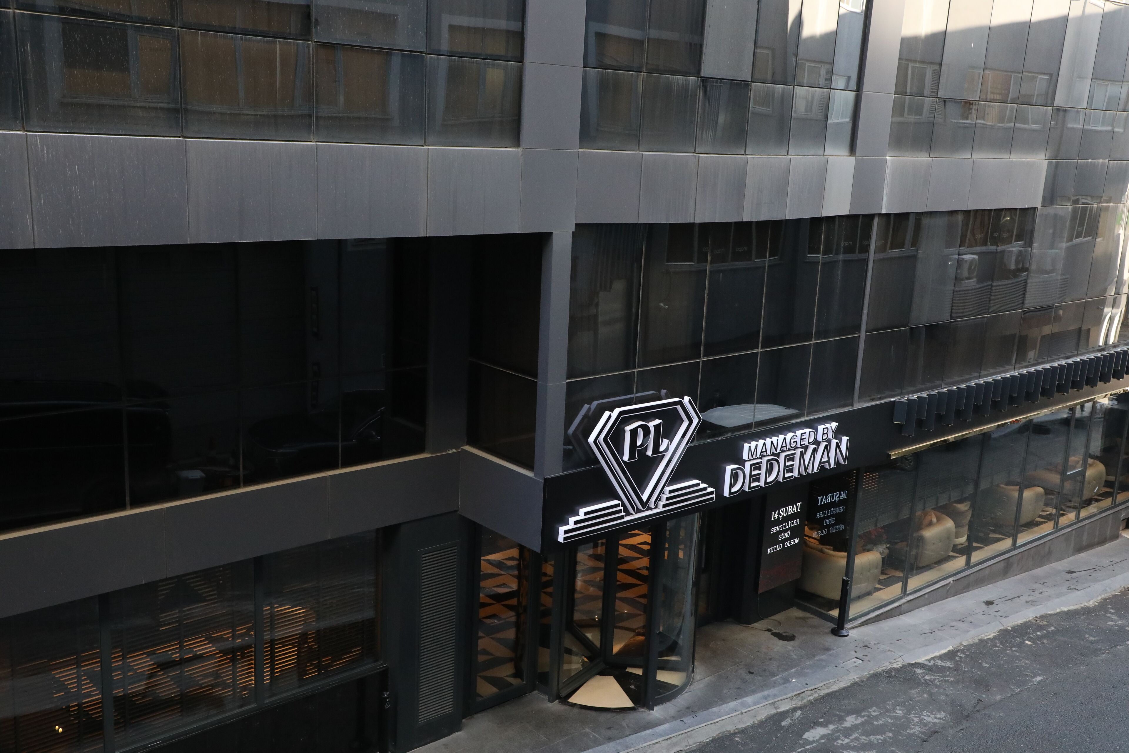 Un edificio moderno con fachada de vidrio, un logotipo destacado y un letrero que indica que es administrado por Nedeman.
