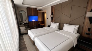 Une chambre d’hôtel avec deux lits, une télévision, un bureau et une chaise.