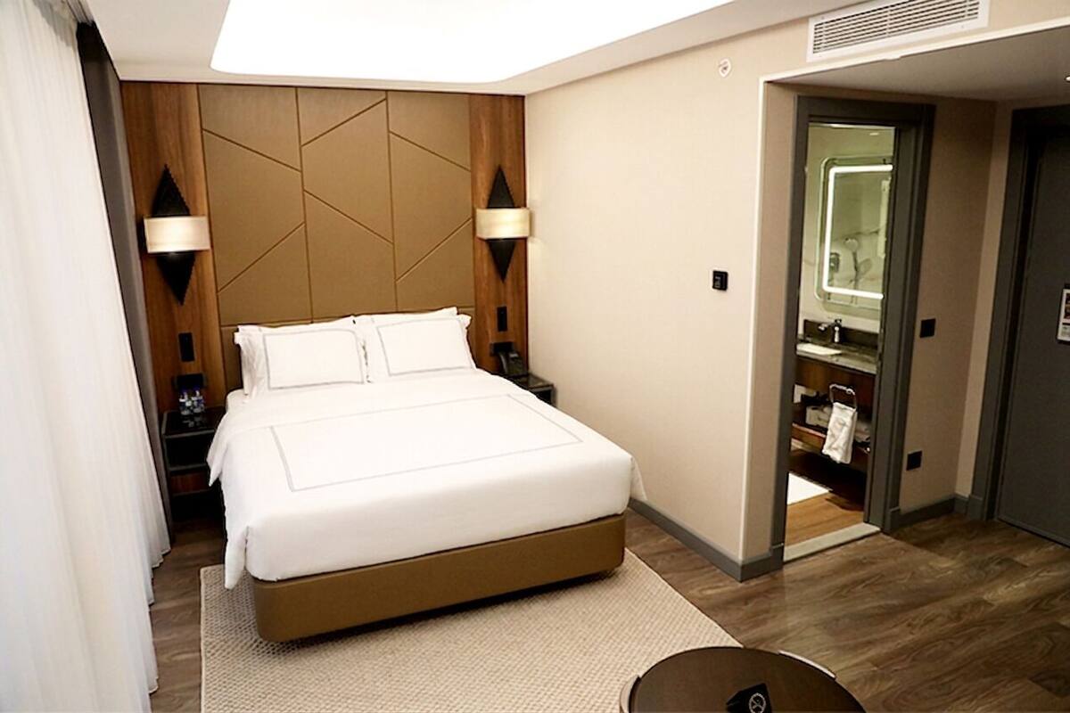 Una camera d'albergo con un letto, abat-jour, uno specchio e un armadio a muro.