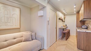 Un interior moderno con un sofá, zona de cocina y taburetes de bar.