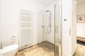 A modern bathroom with a glass-enclosed shower, a toilet, and a radiator. - Global Living Dresden Frauenkirche (Dresden)