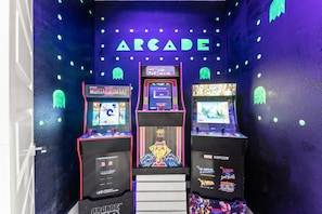 Una hilera de máquinas recreativas con luces de neón y un letrero que dice 'ARCADE'.