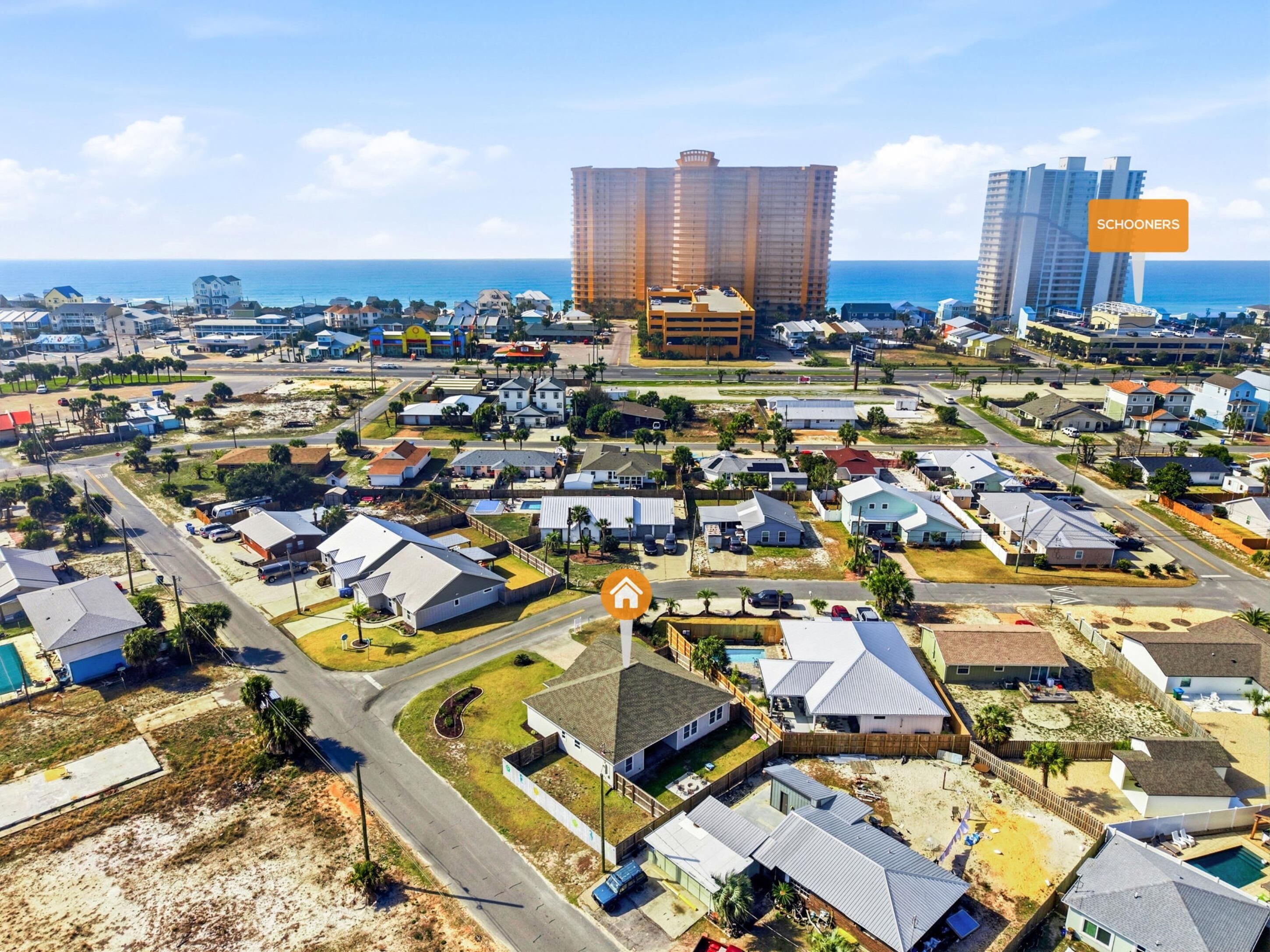 Vista aérea de una zona residencial costera con varias casas, un hotel grande y una playa.