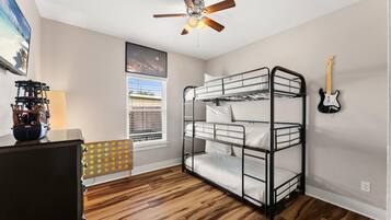 A bunk bed room with a ceiling fan, a guitar, and a window with blinds.