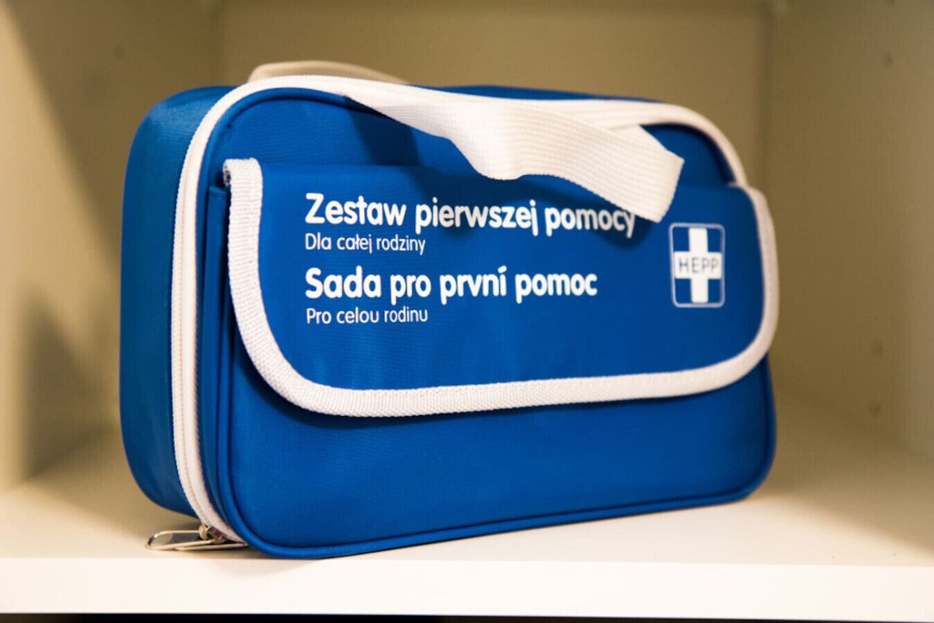 A blue bag with text in Polish, a white zipper, and a small logo on the side.