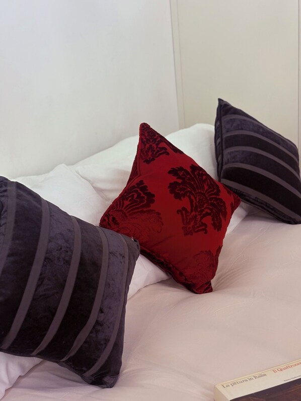 Un lit avec trois oreillers de couleurs et de motifs différents.