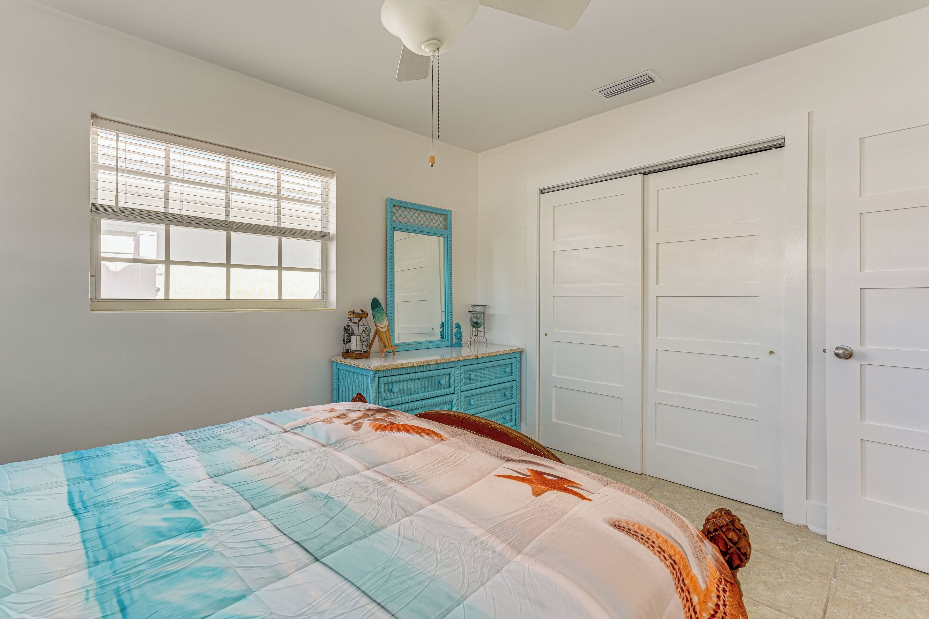 A bedroom with a bed, a dresser, a mirror, and a closet.