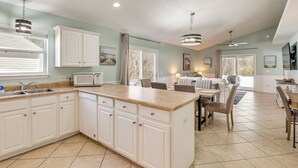 A spacious kitchen with white cabinetry, a central island, and a dining area with chairs and a table. - 1 Mi From Beach, Private Yard + Community Pools (Panama City Beach)