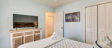 A bedroom with a bed, a television, a wardrobe, and a ceiling fan.