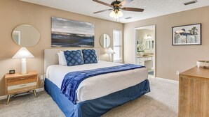 A bedroom with a bed, bedside tables, a ceiling fan, and artwork on the walls. - 1 Mi From Beach, Private Yard + Community Pools (Panama City Beach)