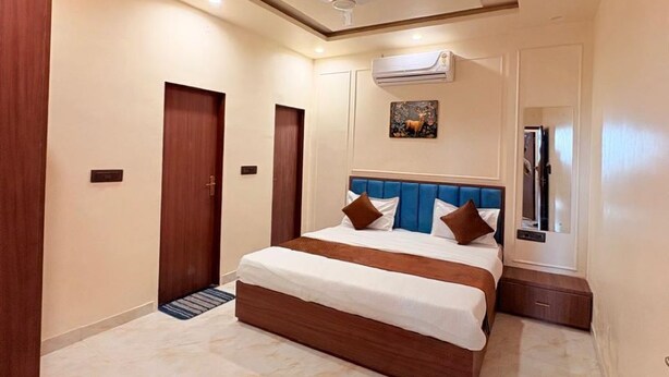 A modern hotel room with a large bed, a ceiling fan, an air conditioning unit, and a small trash bin. - Hotel Shree Shyam and Restuarant (Jaipur)