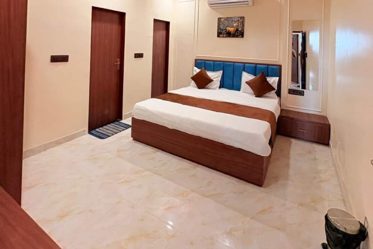 Una habitación de hotel moderna con una cama grande, un ventilador de techo, un equipo de aire acondicionado y un pequeño cubo de basura.