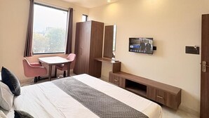A modern hotel room with a large bed, a desk, a chair, a TV, and a wardrobe. - Hotel Shree Shyam and Restuarant (Jaipur)