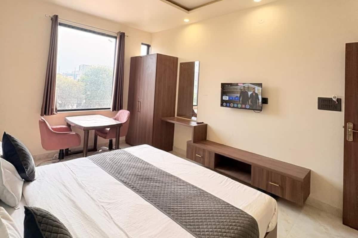 Una habitación de hotel moderna con una cama grande, un escritorio, una silla, un televisor y un armario.