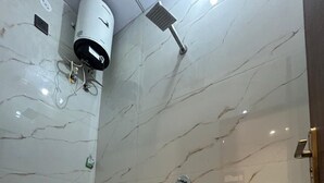 A bathroom with a toilet, a sink, a shower, and a water heater. - Hotel Shree Shyam and Restuarant (Jaipur)