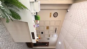 A hotel interior with a staircase, a reception desk, a wall-mounted clock, and a decorative plate. - Hotel Shree Shyam and Restuarant (Jaipur)