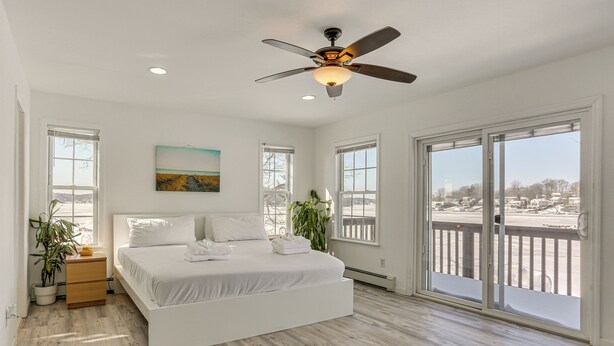 Une chambre spacieuse avec un grand lit, un ventilateur de plafond et un balcon offrant une vue agréable.